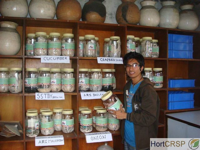 Young man holds jar of seeds and drying beads in vegetable seed repository in Nepal.