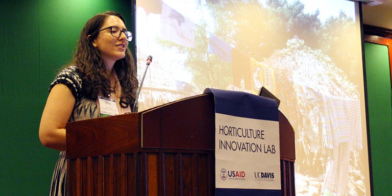 Elyssa Lewis speaking at a podium with USAID and UC Davis logos