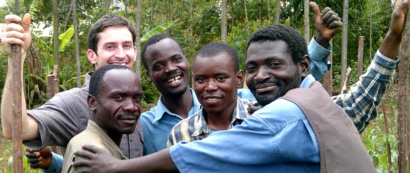 Five men stand smiling under trees