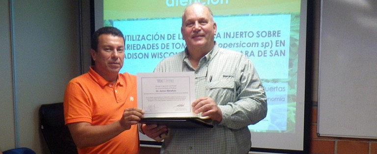 Jim Nienhuis standing with man, holds a certificate out