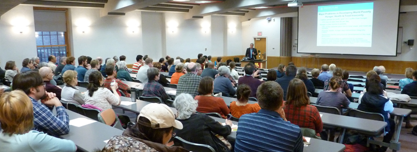 Crowded lecture hall with speaker at front