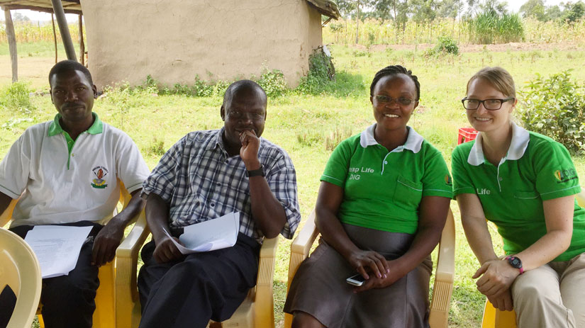 Four people sit smiling outdoors