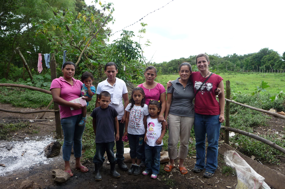 Angel Cruz poses in a plot with farmers and their family