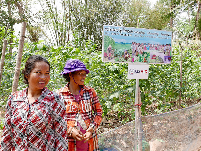 Two women farmers in front of a plot of longbeans