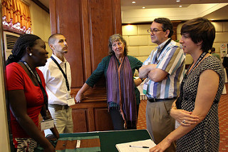 Group of five people around a table in a hotel ballroom, standing and talking