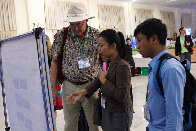 Paull, Theavy, and student look at and discuss a poster