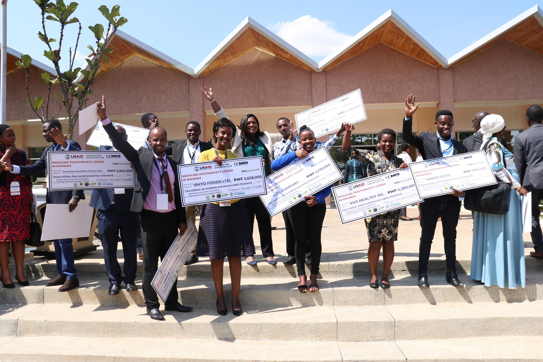 Several competition winners with large checks pose for a photo