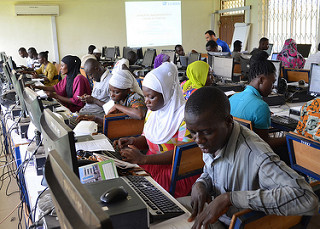 Ghanean students work on computers in a crowded classroom