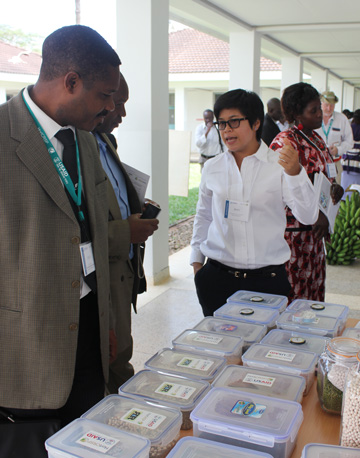 Kenyan volunteer talks with American student around a table showcasing drying beads