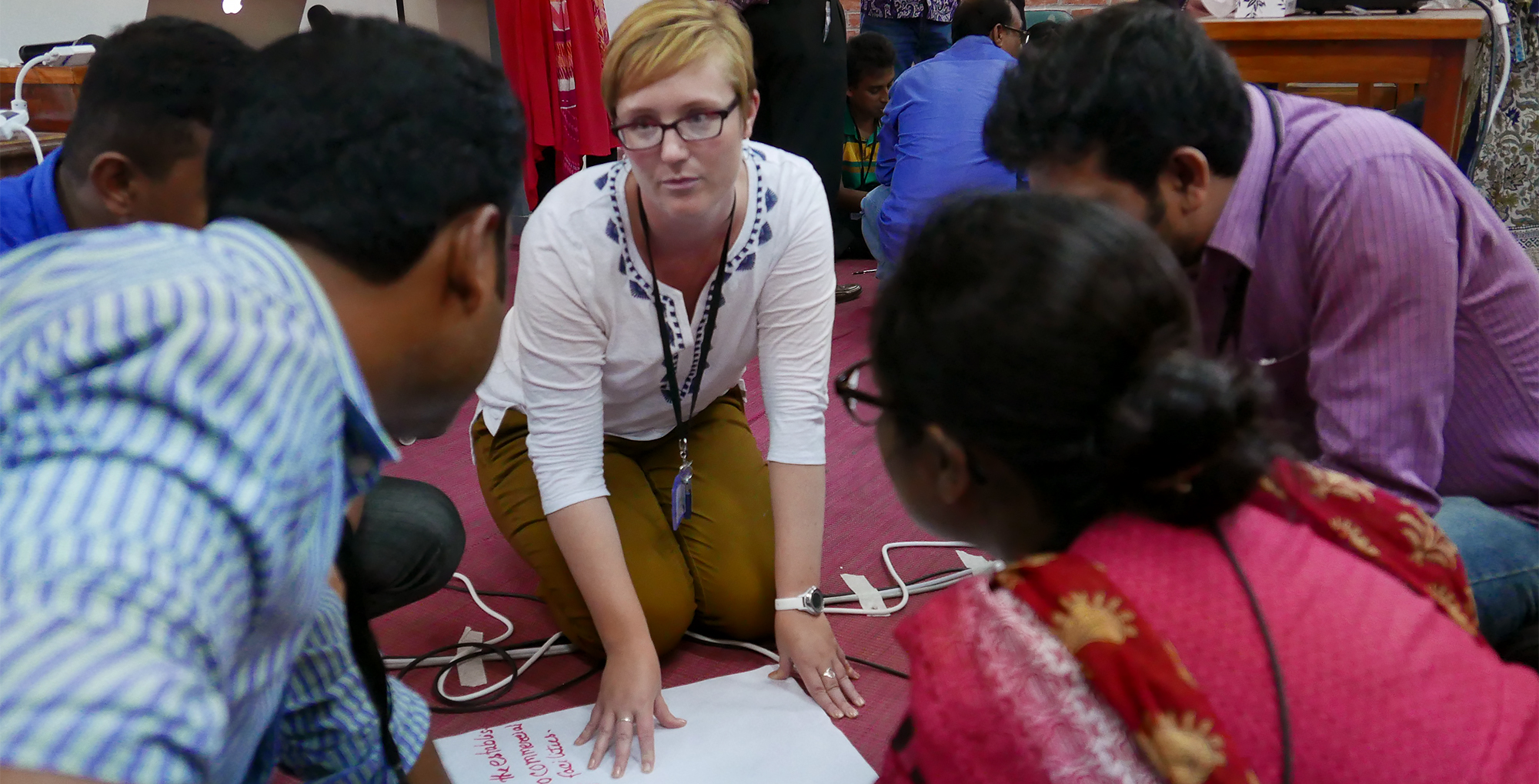 young international professinals discuss horticulture while kneeling on meeting room floor