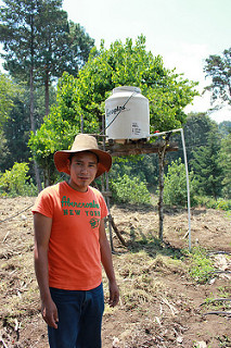 young farmer in field with water tank and tower behind him