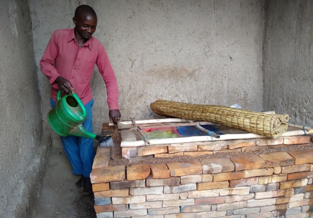 Farmer waters gravel and bricks of a zero-energy cooling chamber, which holds fresh produce inside