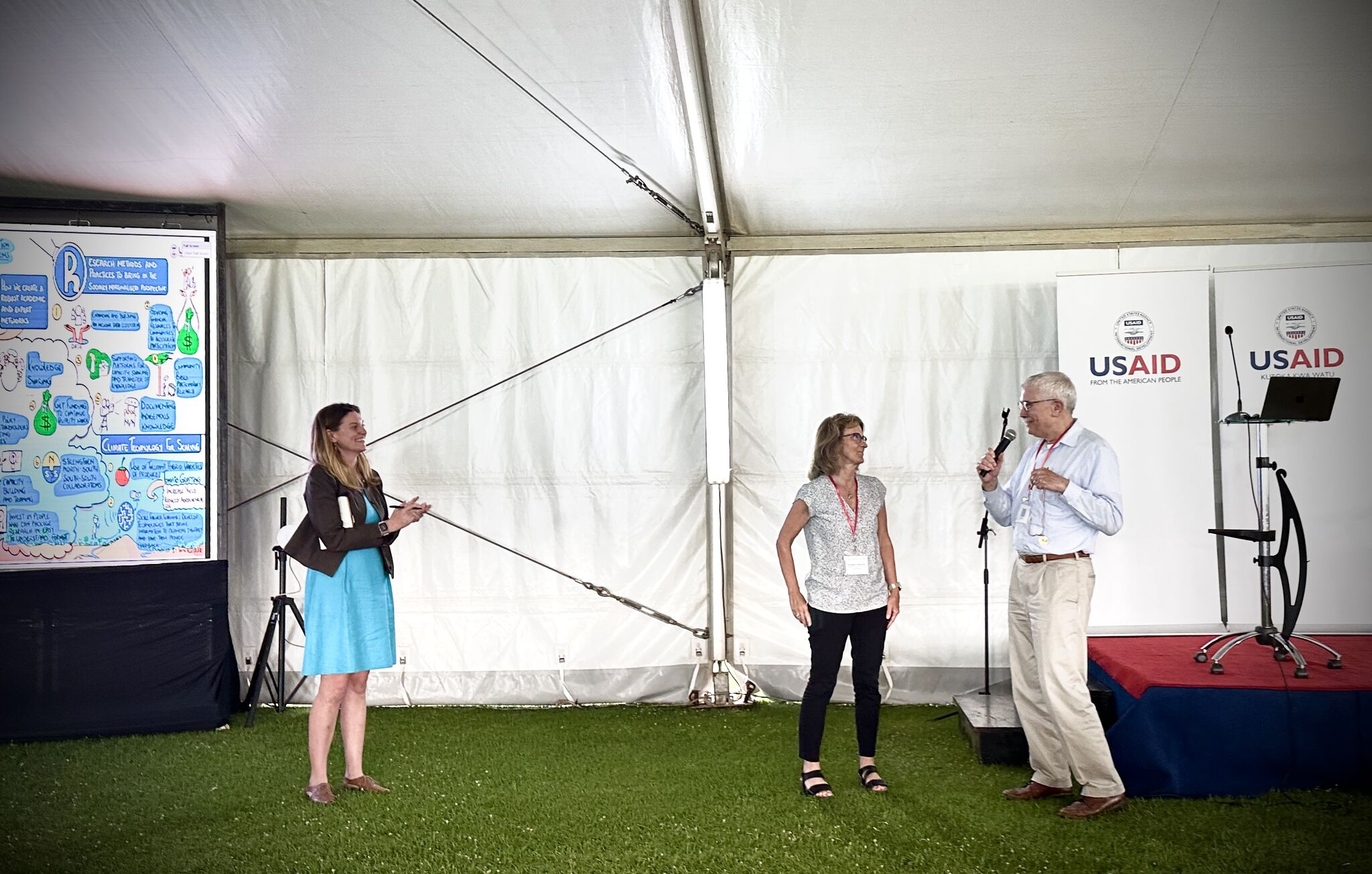 Three individuals before an audience, in a formal farewell to Dr. Beth Mitcham.