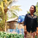 Woman farmer in Cambodia in vegetable farm blog with mulch and drip irrigation tank.