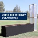 "Using the chimney solar dryer" on an image of the chimney solar dryer in a sunny field