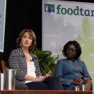 Beth Mitcham speaking on conference stage, next to Jane Ambuko, with two panelists listening, "foodtank" visible in background banner
